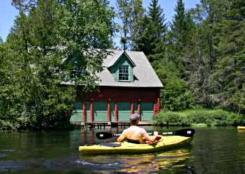 On the Bois Brule, a kayaker paddles by a boathouse.