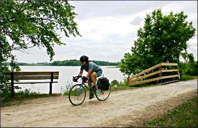 A bicyclist passes Oak Lake on the Luce Line.
