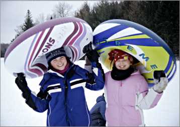 Two young girls at the bottom of a tubing hill.