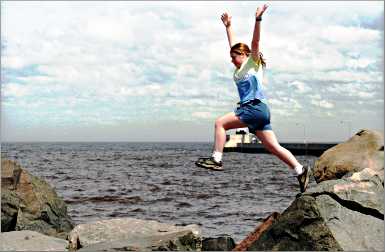 A girl jumps over rocks on Duluth's Canal Park.