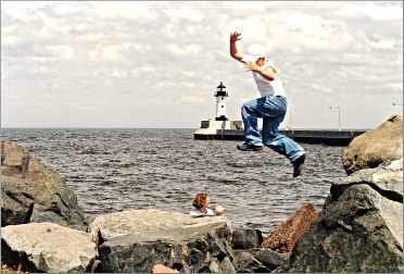 A boy jumps from rock to rock on the shore in Duluth's Canal