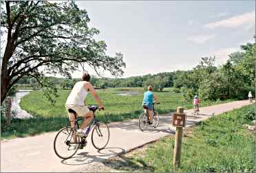 Bicyclists pass an oxbow bend of the Root River on the trail