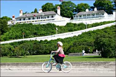 A bicyclist rides by Fort Mackinac.