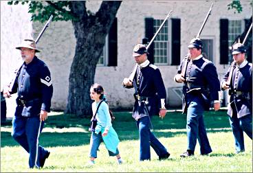 A little visitor marches with soldiers at Fort Mackinac.