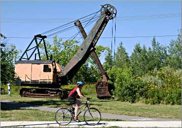 A bicyclist and steam shovel on the Mesabi Trail.
