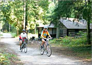 Bicyclists pass a pioneer cabin in Point Beach State Forest.