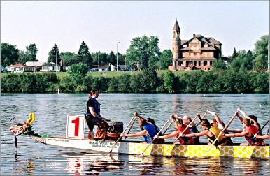 A dragon boat races past Fairlawn Mansion in Superior.
