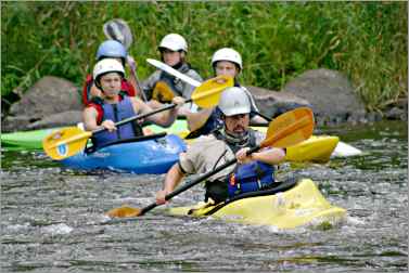 Whitewater kayaking students follow instructor.